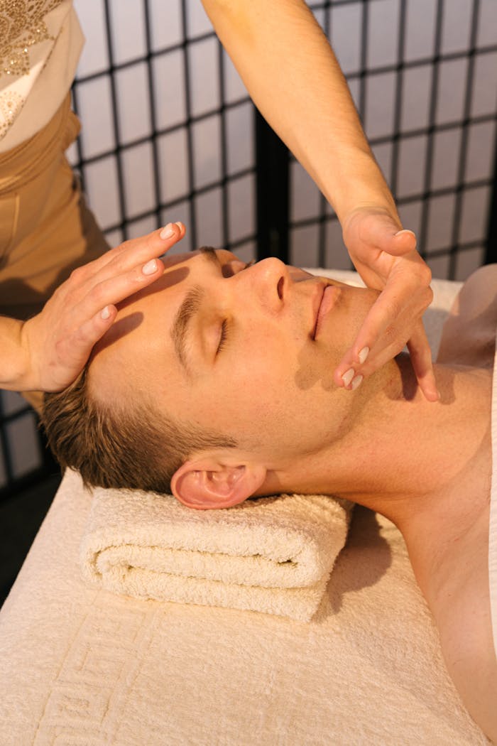 Man receiving a calming face massage at a professional spa, emphasizing relaxation and wellness.