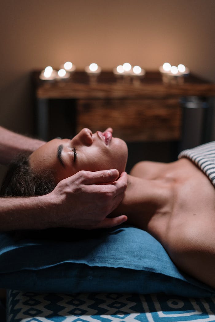 Woman receiving a calming facial massage in a tranquil spa setting with candlelight.